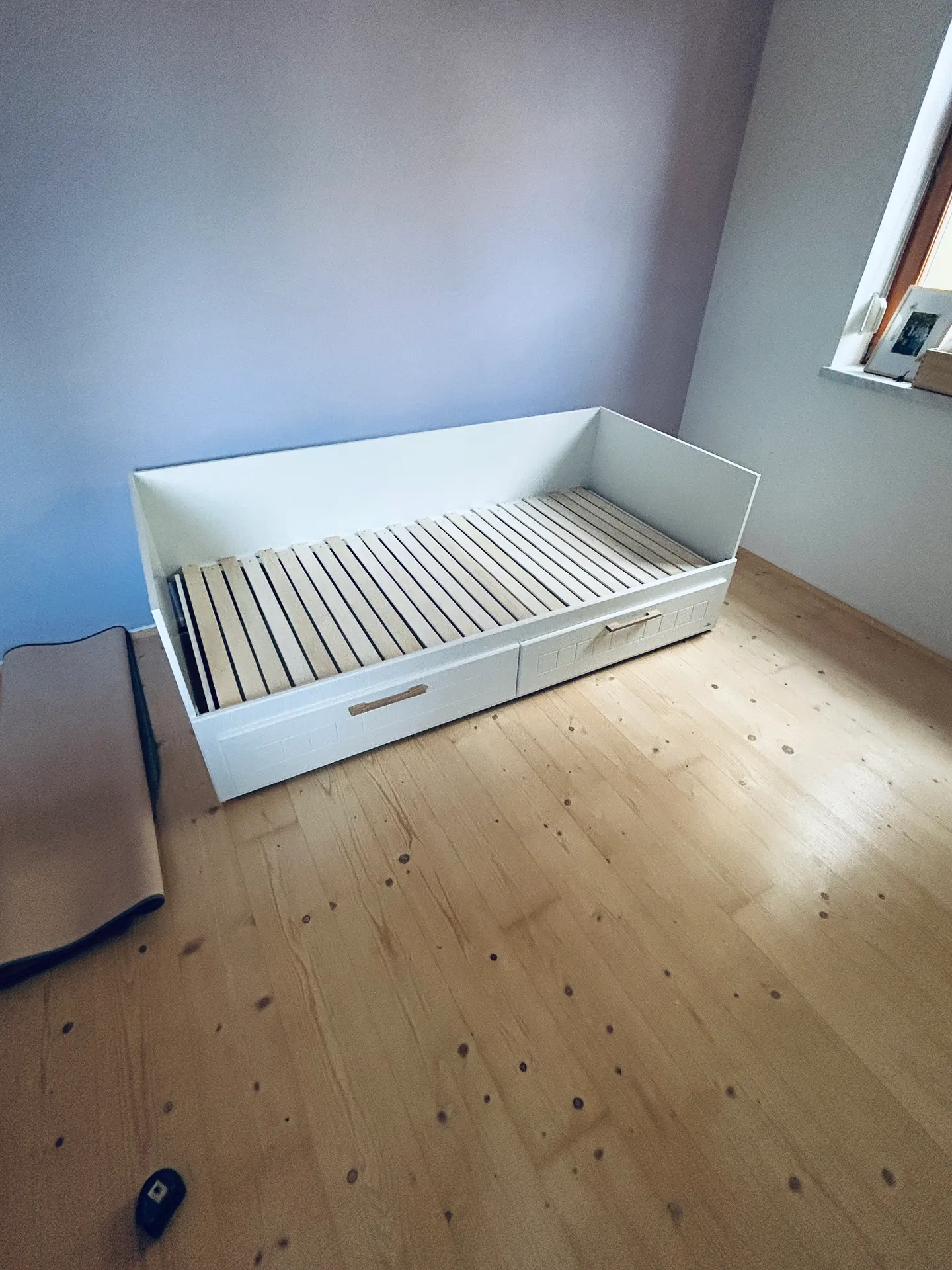Aufgebautes Bett mit Lattenrost im Zimmer